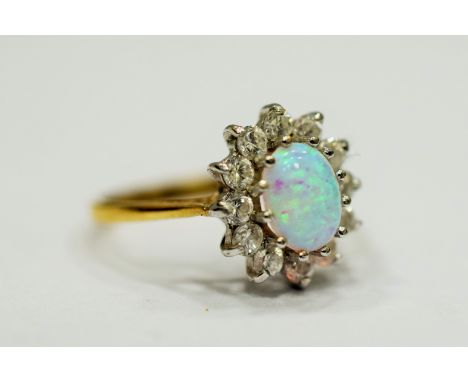 9ct Yellow Gold ring set with a lovely Central Opal which measures 8 x 5mm, surrounded by Clear gemstones.   Finger size 'Q-5