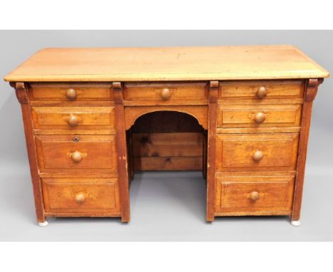 An antique light oak knee hole desk with nine drawers, 50in wide x 28in high x 21.5in 