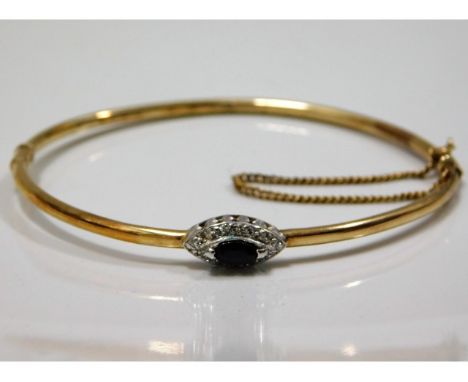 A yellow metal bangle, tests as 9ct gold, set with blue &amp; white stones 4.5g 