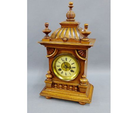 Mahogany cased mantle clock with finials and fluted top over a brass dial with enamel chapter ring with Roman numerals on bun