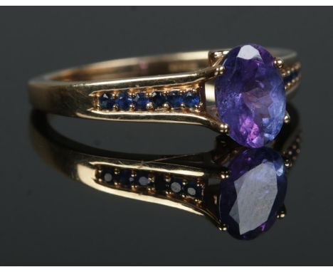 A 9ct Gold Tanzanite solitaire ring, set with smaller stones to the shoulders and a small diamond to either side of the main 