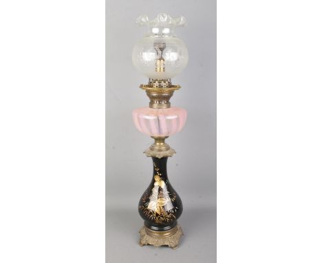 A brass and glass oil lamp featuring hand painted gilt floral decoration and pink opaline reservoir. Lamp has been converted 