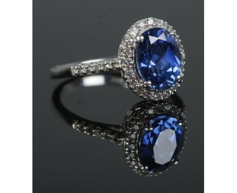 A 10ct White Gold ring, set with large faceted blue stone surrounded by pasted stones and having paste set shoulders. Stamped