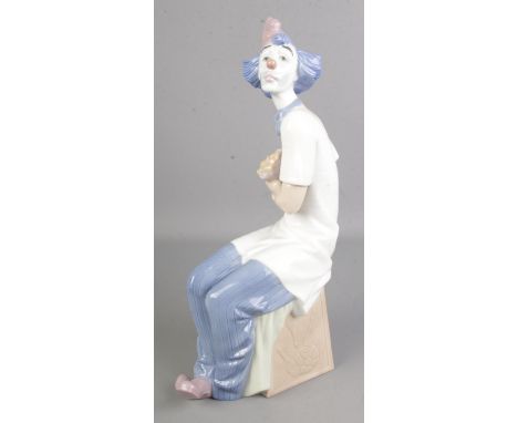 A large Nao by Lladro of a seated clown with flowers