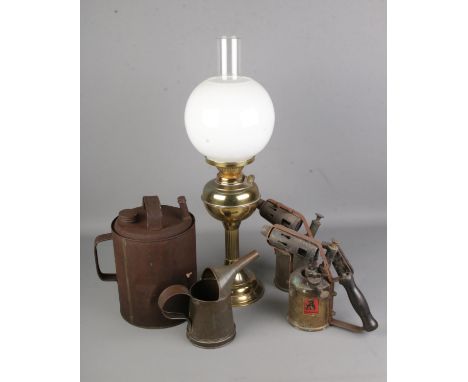 A brass oil lamp with glass shade with two vintage blowtorches, oil jug and can