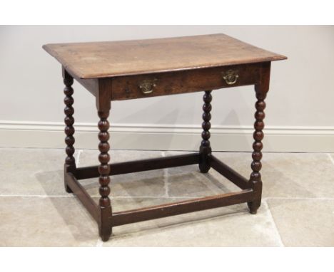 A 17th century oak side table, the rectangular plank top with a frieze drawer, raised upon four bobbin-turned and block suppo