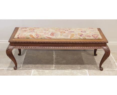 A mid 20th century carved hardwood and upholstered long stool, the rectangular drop in crewel work seat within a frame carved