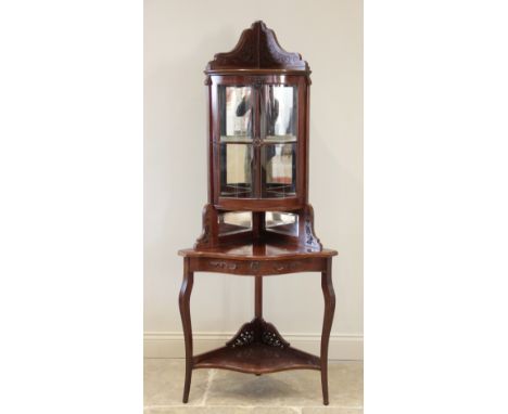 An Edwardian mahogany freestanding corner display cabinet, the bow front glazed cabinet above a galleried mirror back serpent