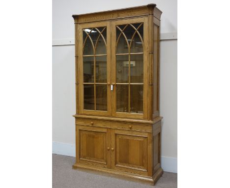 Light oak bookcase on cupboard, Gothic style raised bookcase with cluster column pilasters, astragal glazed doors, two drawer