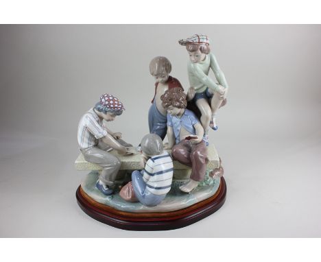 A large Nao porcelain figure group of boys playing cards, on wooden base, 30cm high