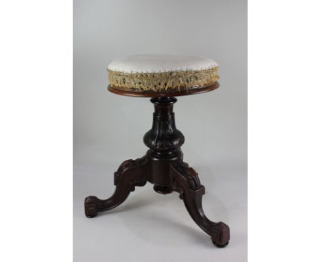 A Victorian mahogany adjustable piano stool with heavily carved tripod base