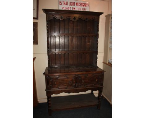 A carved oak dresser of two shelves over two short drawers, on turned legs with uniting shelf stretcher, 107cm