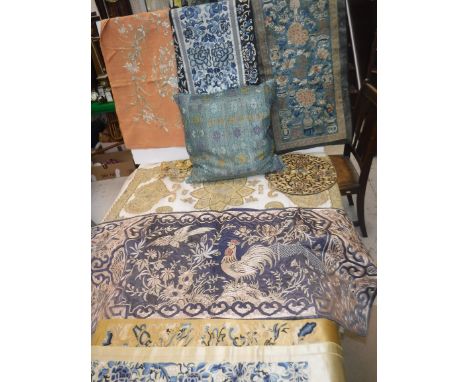 A collection of various Oriental textiles to include a Chinese panel, the blue ground set with floral sprays in vases with pe