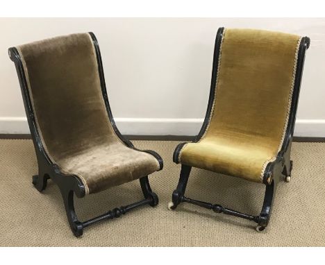 Two Victorian ebonised and gilt or brass embellished nursing chairs of scroll form on scroll supports united by turned stretc