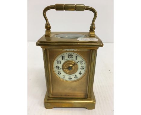 A circa 1900 French lacquered brass cased carriage clock, the circular porcelain dial with indistinct retailer's inscription,