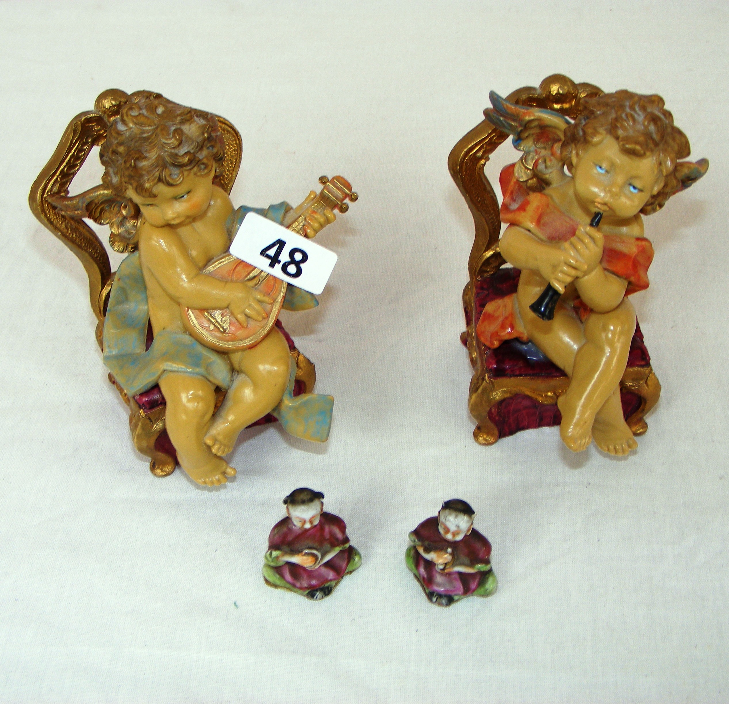 A pair of seated cherub figurines and two miniature oriental figurines