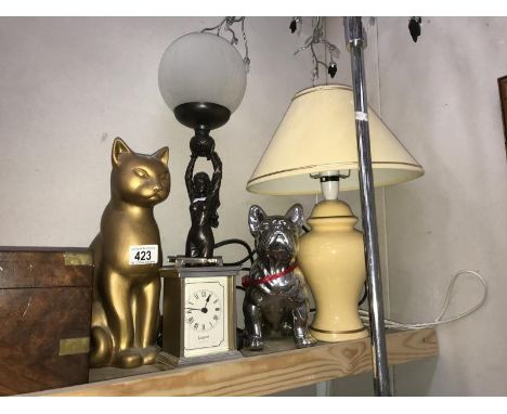 A table lamp, a figural lady lamp, a cat and a dog ornament and a modern carriage clock