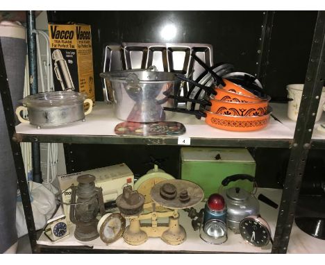 2 shelves of retro and vintage household goods including brand new 70's pots and pans, scales, storm lamp, clocks etc.