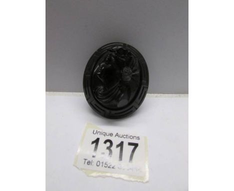 A Whitby jet cameo of a young woman with flowers in a Greek pattern surround.