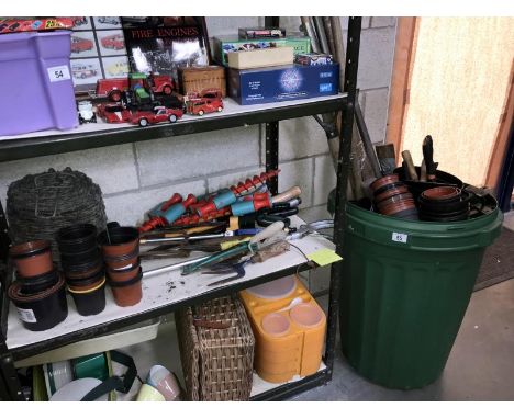 A shelf of gardening tools, pots, a roll of barbed wire and a plastic bin of tools