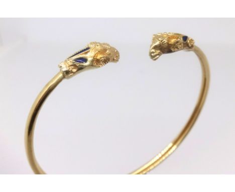 An 18ct gold yellow metal rams head bangle set with blue stone, approx. 11.5gms.