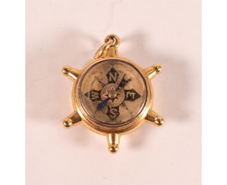 19th century 18ct gold novelty fob in the form of a ships wheel, gross weight 12.5g.  Hardstone on one side, a compass on the