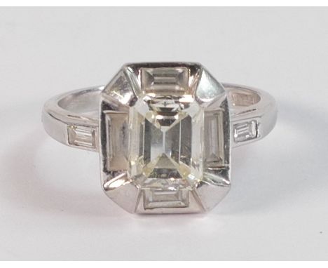 Platinum Art Deco style diamond ring, with square set ring head with central emerald cut diamond 6.2mm x 8mm x 4mm, totalling