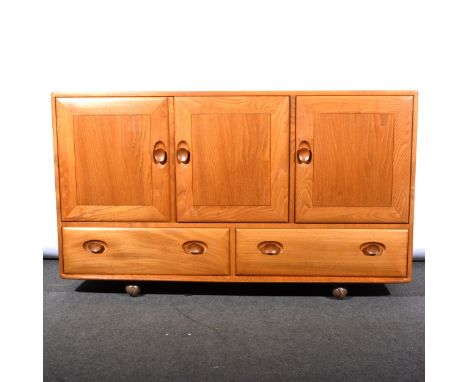 A light elm sideboard by Ercol, model 429, with three cupboard doors over two drawers, on ball casters, width 130cm, depth 45