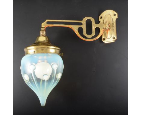 An Arts and Crafts wall light with opalescent drop shade, circa 1900, the brass scone and arm cast supporting a teardrop form