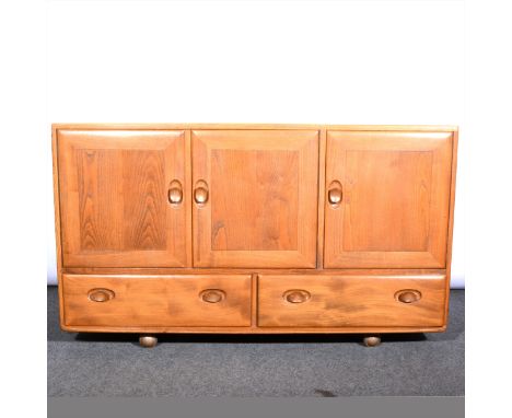 A light elm sideboard by Ercol, model 429, with three cupboard doors over two drawers, on ball casters, width 130cm, depth 45