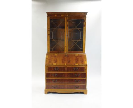 A reproduction walnut bureau bookcase, with astragal glazed doors above a fall front desk over two short and three long drawe