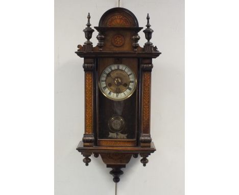 A walnut and parquetry style Vienna style wall clock, with arched and finialled pediment above an arched glazed door enclosin