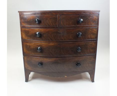 A Regency mahogany bowfront chest of two short and three long graduated cockbeaded drawers with ebonised knob handles above a
