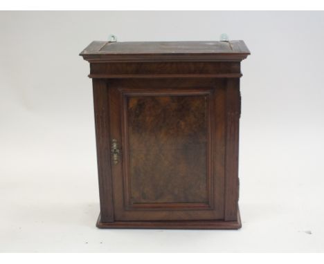 An French walnut wall hanging cupboard, 19th century, the stepped cornice above an indented fielded panel door, flanked by fl