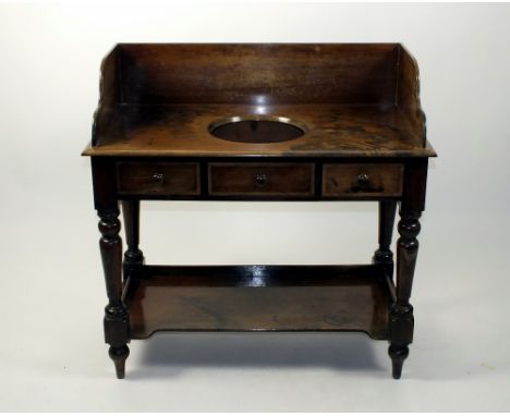 A Victorian mahogany washstand, the low panel back above a recess and false drawer front flanked by two short drawers raised 