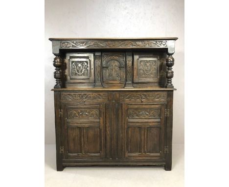 Substantial oak Arts and Crafts court cupboard with extensive carving, with baluster columns, three cupboards over, two drawe