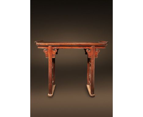 A CHINESE HONGMU ALTAR TABLE KANGXI 1662-1722 The rectangular top with raised scroll ends, the frieze carved with stylised cl