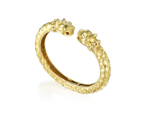 Crafted out of 18K yellow gold, featuring two lion heads, set with cabochon emerald eyes, the cuff accented with raised textu