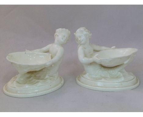 A pair of 20th century Worcester porcelain shell salts in the form of a merman and a mermaid holding a scallop shell, numbere
