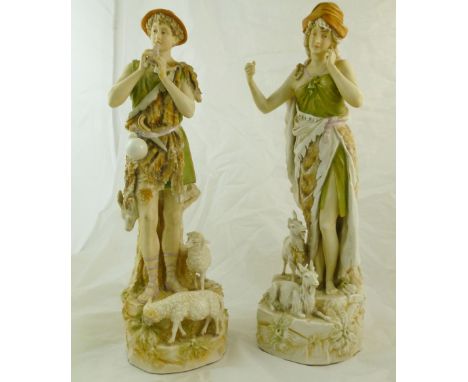 A pair of Royal Dux figures, of a shepherd playing pan-pipes, (pipes at fault with missing piece present), and a female goat 