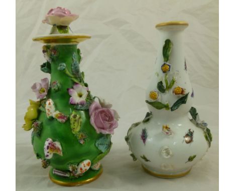 A 19th century porcelain lidded vase with floral and shell encrusted body, the lid with rose head finial, the base with paint