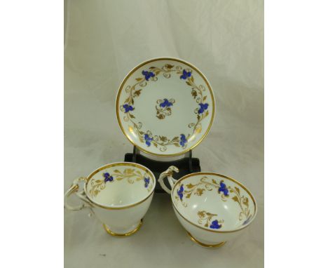 An H & R Daniel porcelain trio, plain edge shape variation C, decorated in blue and gilt with trailing leaves and fruit, numb