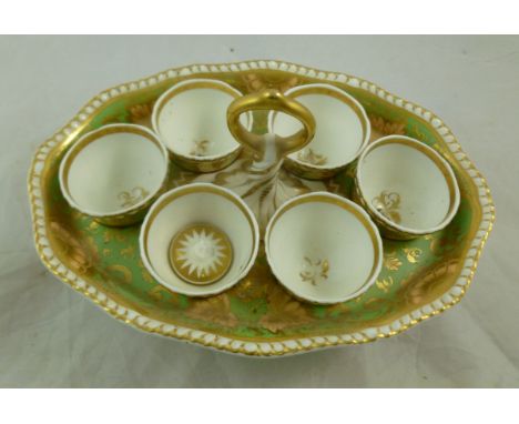 An H & R Daniel porcelain egg cup stand, second gadroon shape, with green ground and apricot and gilt scrolling vine and frui