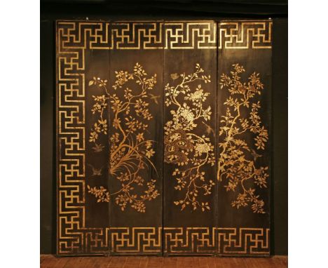 A Chinese lacquered part screen,probably 19th century, the four panels decorated in gilt with flowering foliage within a Gree