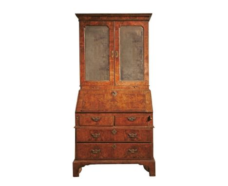 A George I walnut bureau bookcase,with moulded cornice over mirrored doors with bevelled plates, enclosing an interior fitted