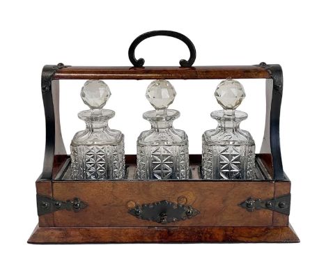 A Victorian figured walnut tantalus. Of diminutive proportions, fitted three cut glass bottles and stoppers, with brass mount