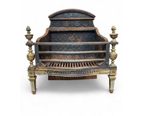 A Regency style brass and steel fire grate. Circa 1900, with a shaped back, slightly bow front, with brass flame finials and 