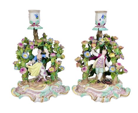 A pair of Meissen candlestick figure groups. Circa 1900, each modelled with a figure dancing beneath an arbour encrusted with