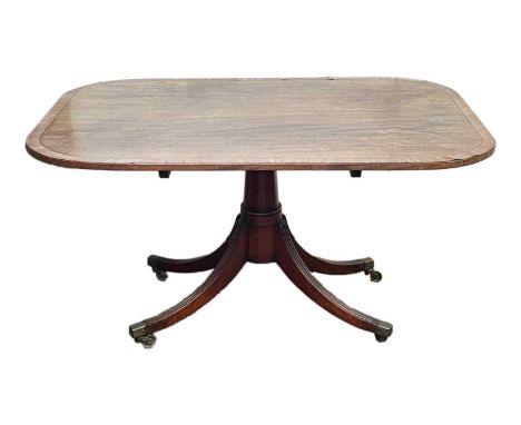 A Regency mahogany and crossbanded breakfast table. The rectangular tilt top with rounded corners and raised on a turned pill