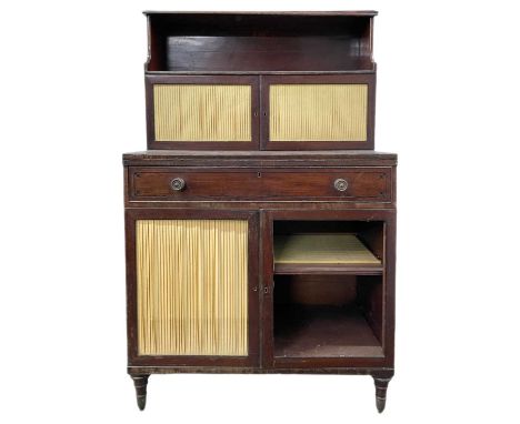 A Regency mahogany chiffonier writing cabinet. The galleried superstructure fitted a shelf and two doors with pleated silk pa